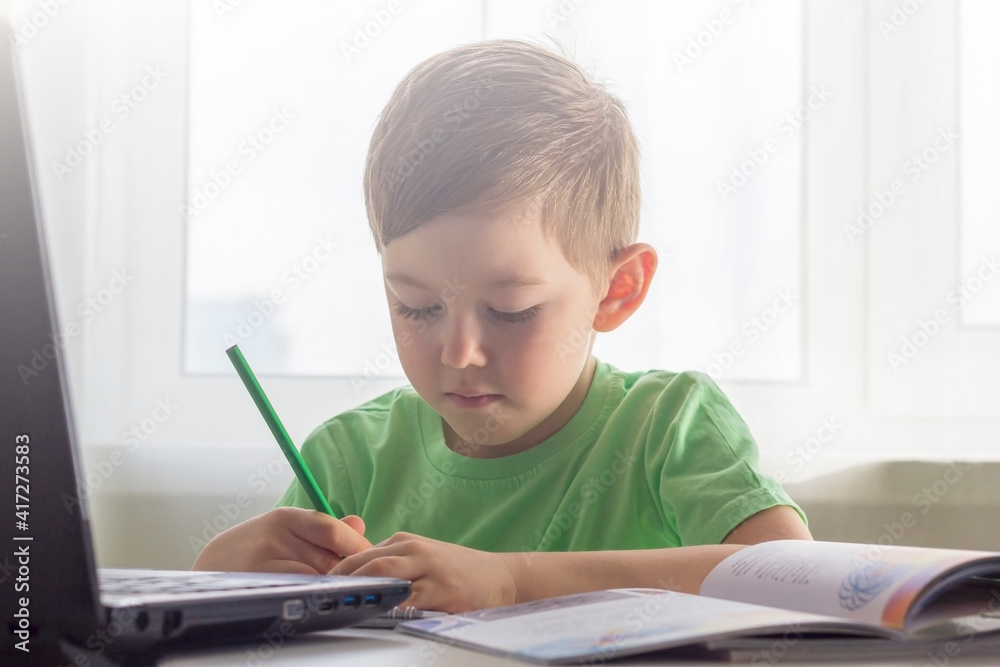 Distance learning, online education. Social distance and self-isolation during quarantine. Preschooler or schoolboy studying at home with notebook and doing homework for development school. Distance learning, online education. Social distance and self-isolation during quarantine. Preschooler or schoolboy studying at home with notebook and doing homework for development school.