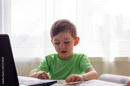 Distance learning, online education. Social distance and self-isolation during quarantine. Preschooler or schoolboy studying at home with notebook and doing homework for development school.