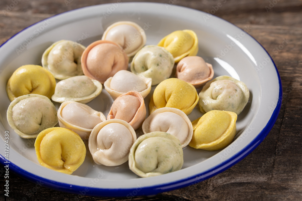 Traditional Russian dumplings made from multi-colored dough. Dumplings on a wooden board in an enamel plate. Cooking concept. Traditional Russian dumplings made from multi-colored dough. Dumplings on a wooden board in an enamel plate. Cooking concept.