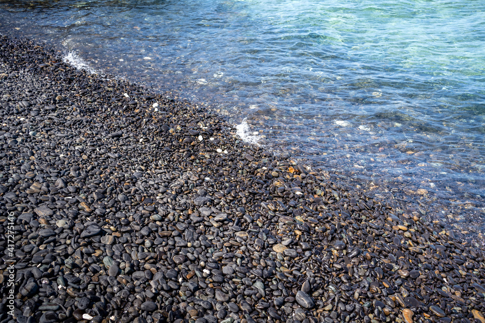 Ko hin-ngam Adang island Satun thailand, Sea pebble beach with multicoloured stones, transparent waves with fog. Ko hin-ngam Adang island Satun thailand, Sea pebble beach with multicoloured stones, transparent waves with fog.