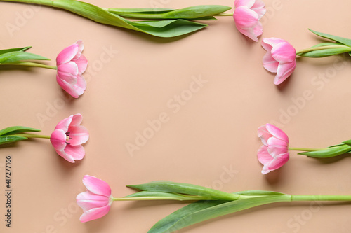 Frame made of beautiful tulip flowers on color background
