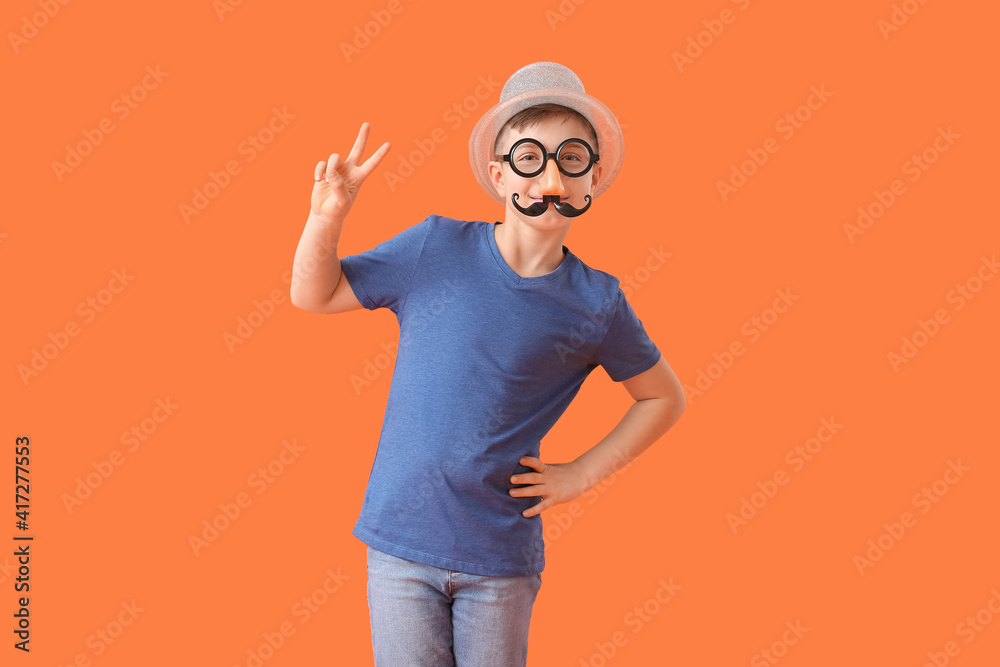 Little boy in funny disguise showing victory gesture on color background. April Fools Day celebration Little boy in funny disguise showing victory gesture on color background. April Fools Day celebration