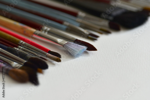 Set of various brushes for the artist, close-up on a white paper background.