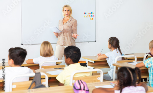 Portrait of female teacher lecturing to children at elementary school