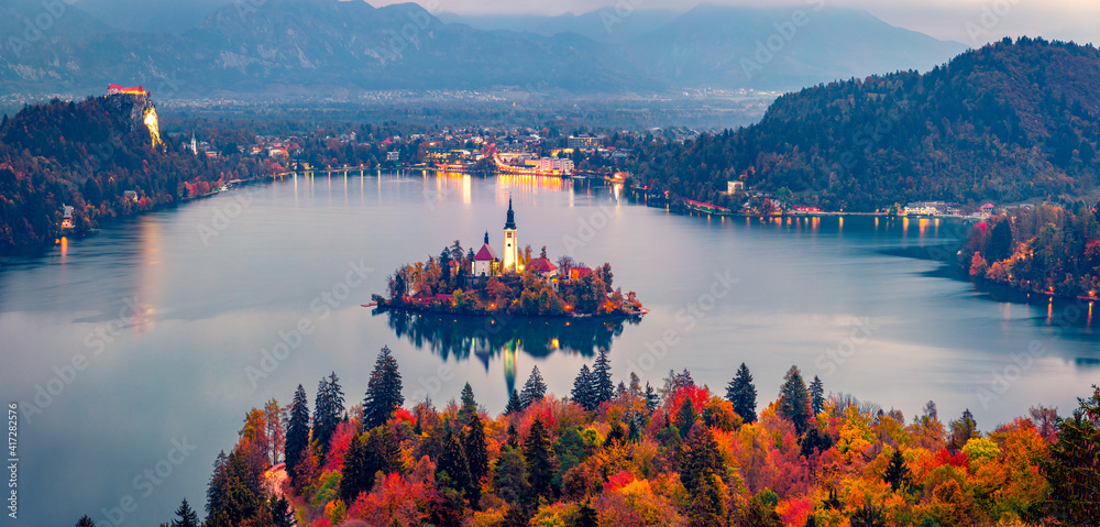 Aerial landscape photography. Colorful morning scene of Pilgrimage Church of the Assumption of Maria. Aerial autumn view of Bled lake, Julian Alps, Slovenia, Europe. Traveling concept background.