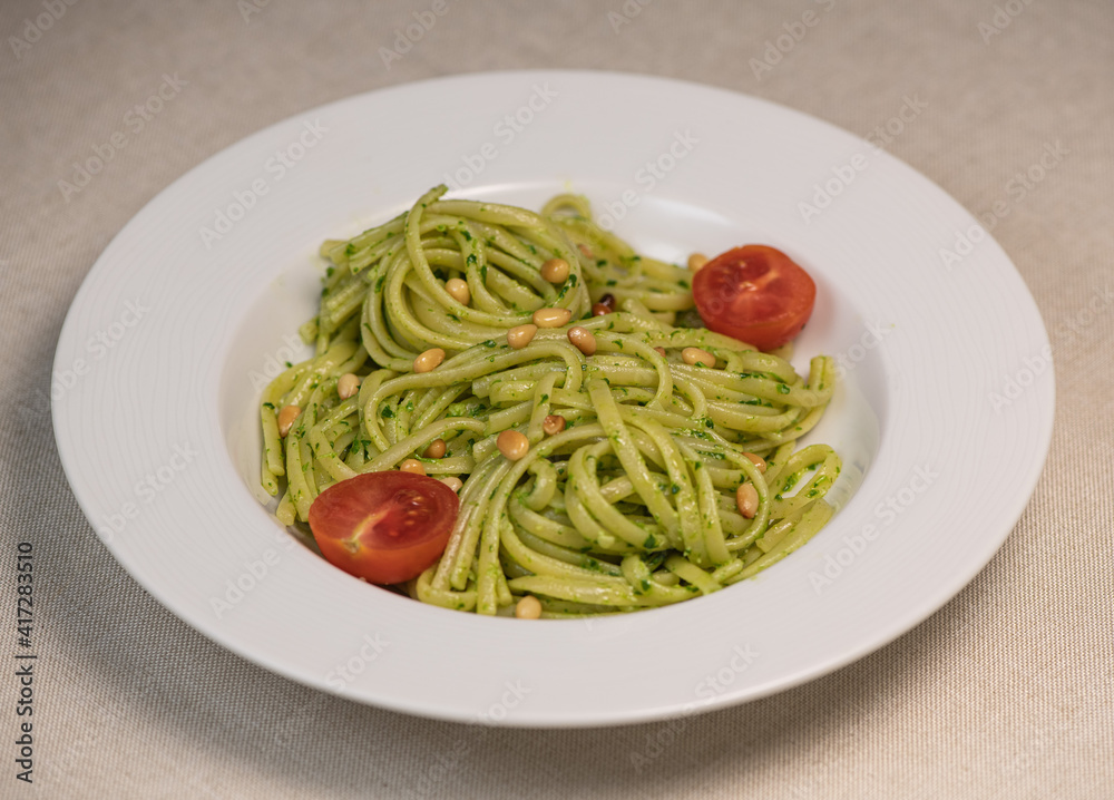 Green spinach spaghetti with cheese and tomato on wooden table Green spinach spaghetti with cheese and tomato on wooden table