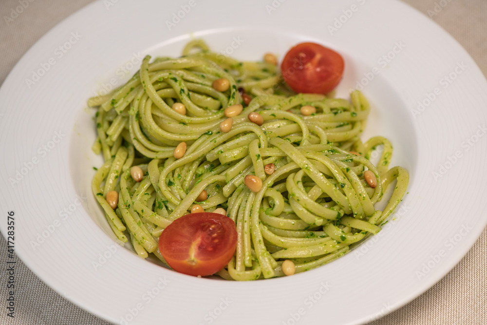 Green spinach spaghetti with cheese and tomato on wooden table