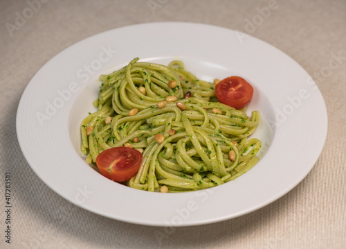 Green spinach spaghetti with cheese and tomato on wooden table
