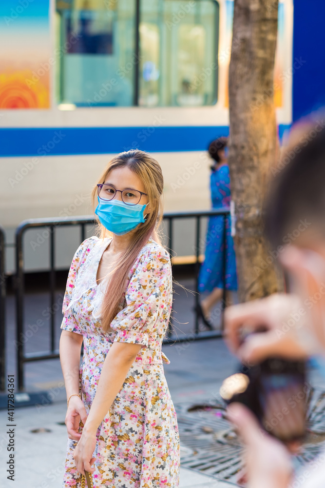 Young millennials couple wearing protective face masks and showing their love outdoor in Ho Chi Minh City during Covid-19