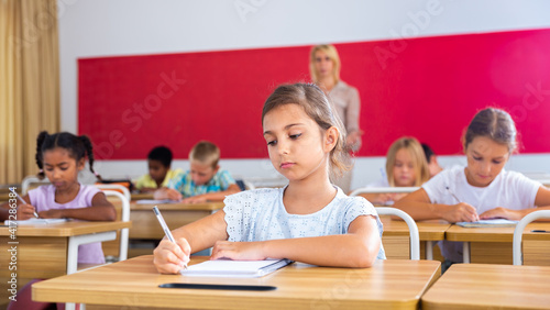 Portrait of girl who is posing at the desk in the classroom elementary school