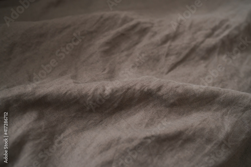 brown crumpled linen bed cover with sunlight from window