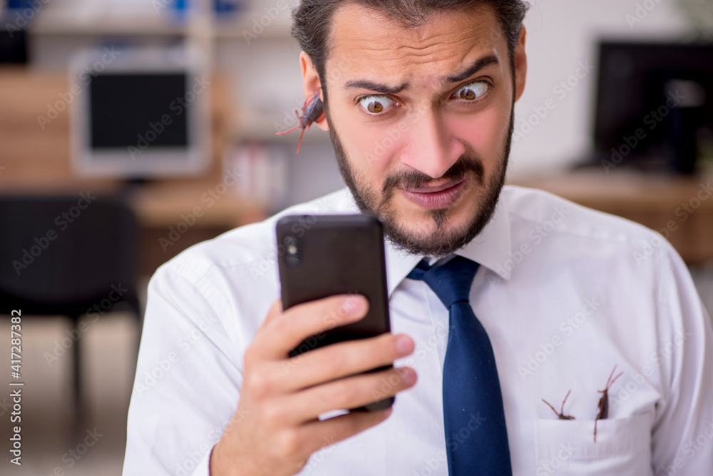 Young male employee and too many cockroaches in the office