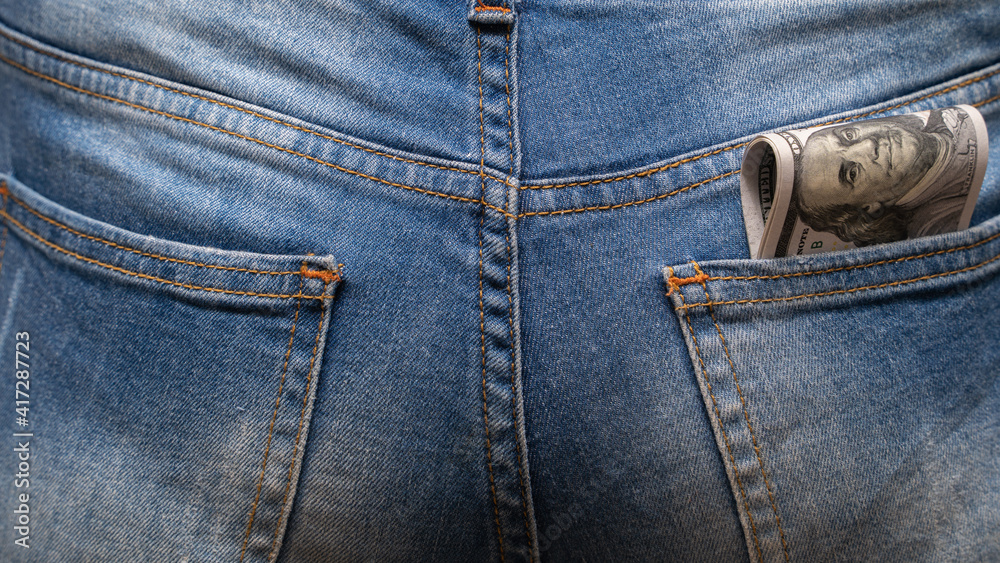 Cash in your pocket. Folded hundred dollar bills stuck out of the back pocket of blue jeans. Money saving concept. Cash in your pocket. Folded hundred dollar bills stuck out of the back pocket of blue jeans. Money saving concept.