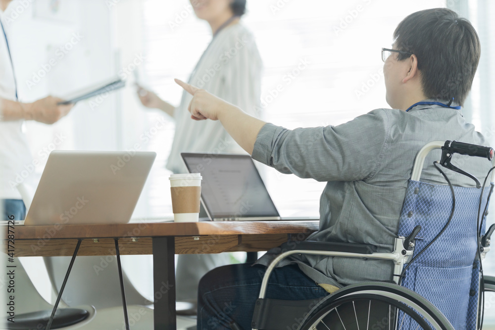 Obraz premium オフィスで働く車椅子の男性