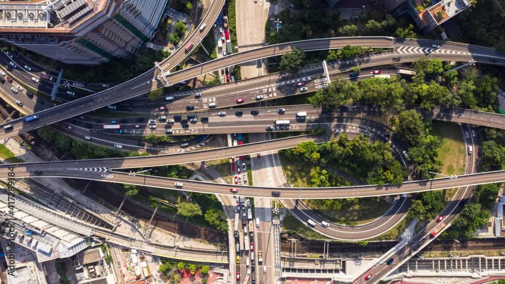Top down view of a traffic time lapse in a busy highway intersection with railroad tracks in the crowded Kowloon district in Hong Kong