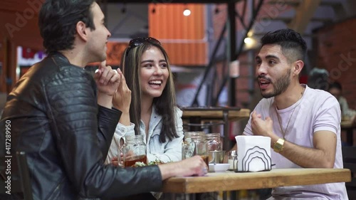 Three friends chatting while eating in restaurant
