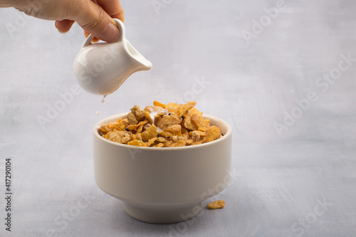 bowl of corn flakes cereals and spoon isolated on grey background. photo