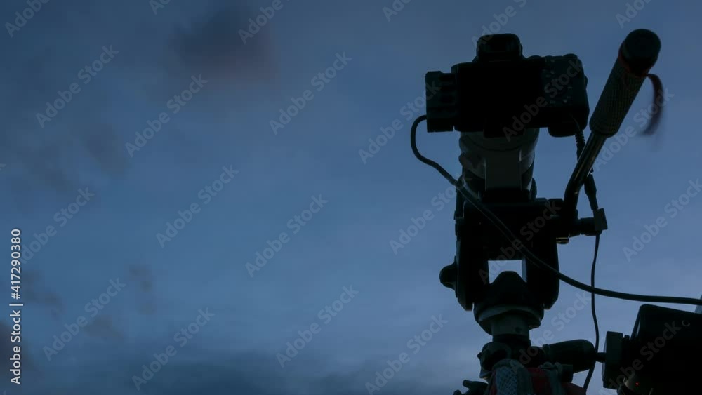 Professional camera on tripod against sky taking film video or shooting images pictures. Time lapse Professional camera on tripod against sky taking film video or shooting images pictures. Time lapse