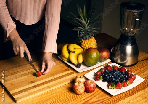 Girl cutting a strawberry for a smoothie