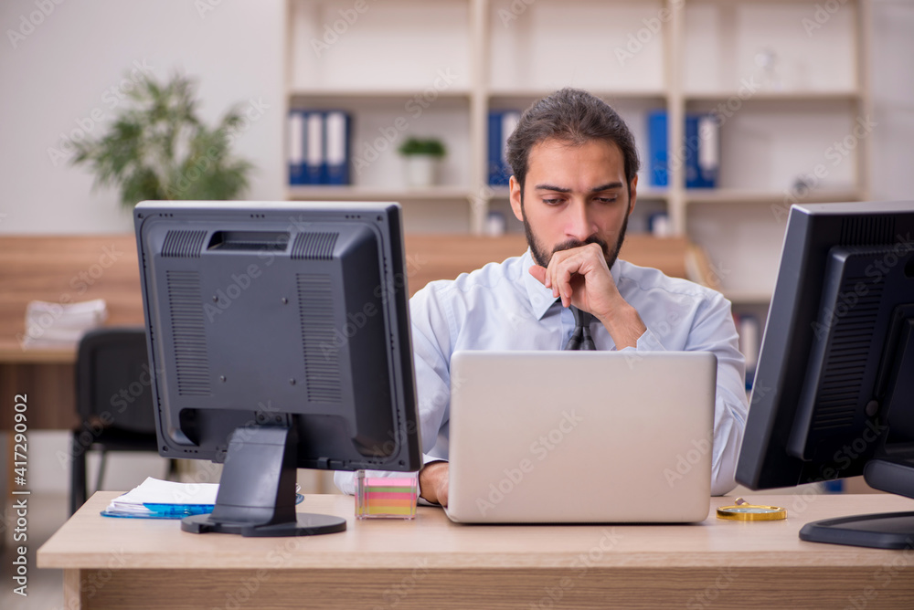 Young male employee in multitasking concept Young male employee in multitasking concept