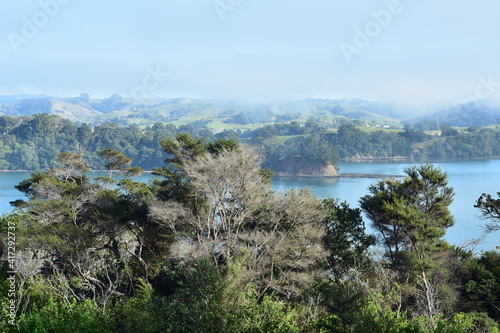 Morning mist disappearing from above calm waters of Mahurangi Harbour growing in bays along harbour bays.