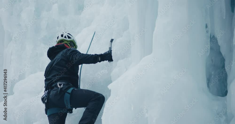 Climber man ice climbing frozen waterfall winter extreme sport scene