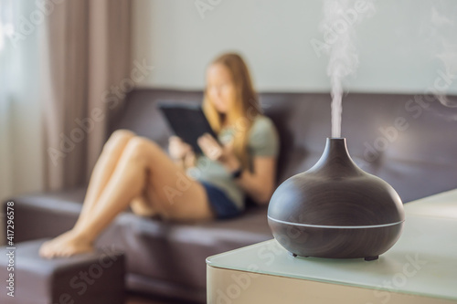 Aromatherapy Concept. Wooden Electric Ultrasonic Essential Oil Aroma Diffuser and Humidifier. Ultrasonic aroma diffuser for home. Woman resting at home photo