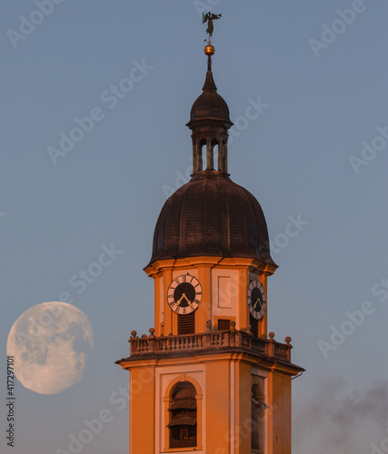 Petrini Kirche Kitzingen im Licht der aufgehenden Sonne im Hintergrund der sinkende Mond  photo