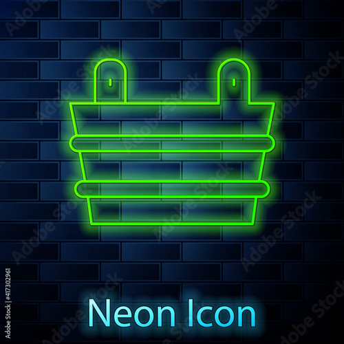Glowing neon line Sauna bucket icon isolated on brick wall background. Vector.