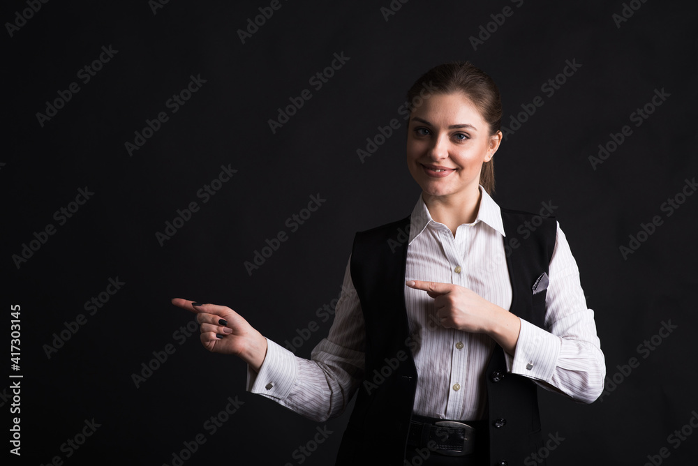 Portrait of a businesswoman who points her finger towards copyspace in the studio on a black background