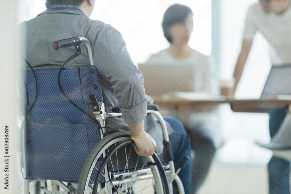 Obraz premium オフィスで働く車椅子の男性