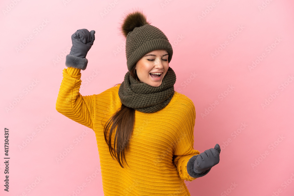 Young caucasian girl with winter hat isolated on pink background celebrating a victory Young caucasian girl with winter hat isolated on pink background celebrating a victory