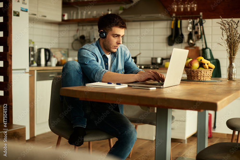 Young man typing an e-mail while working on laptop at home. Young man typing an e-mail while working on laptop at home.