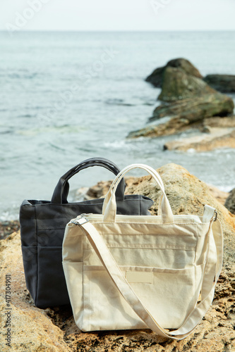 Stylish eco bags outdoor on big sea stone against sea