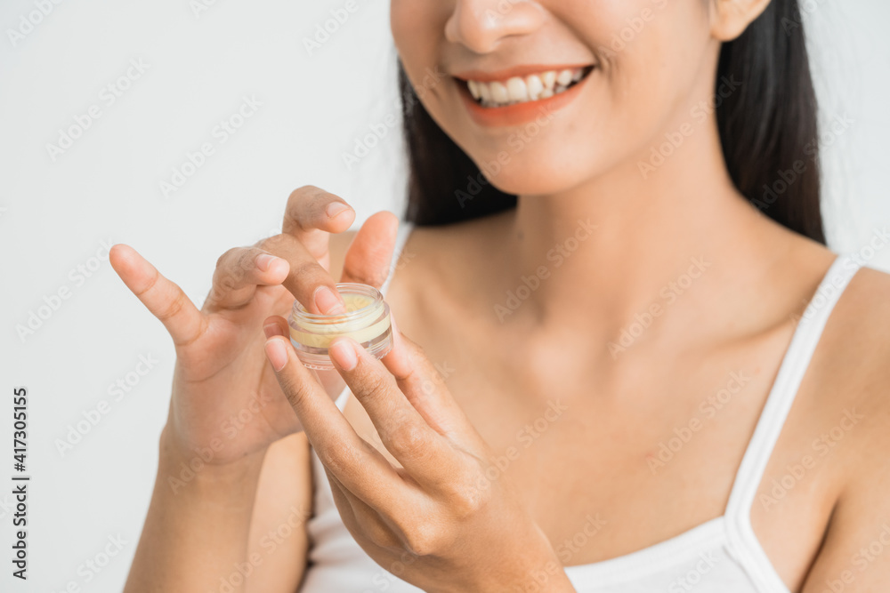 beautiful young asian woman applying cosmetic cream on her face. lip balm - obrazy, fototapety, plakaty 
