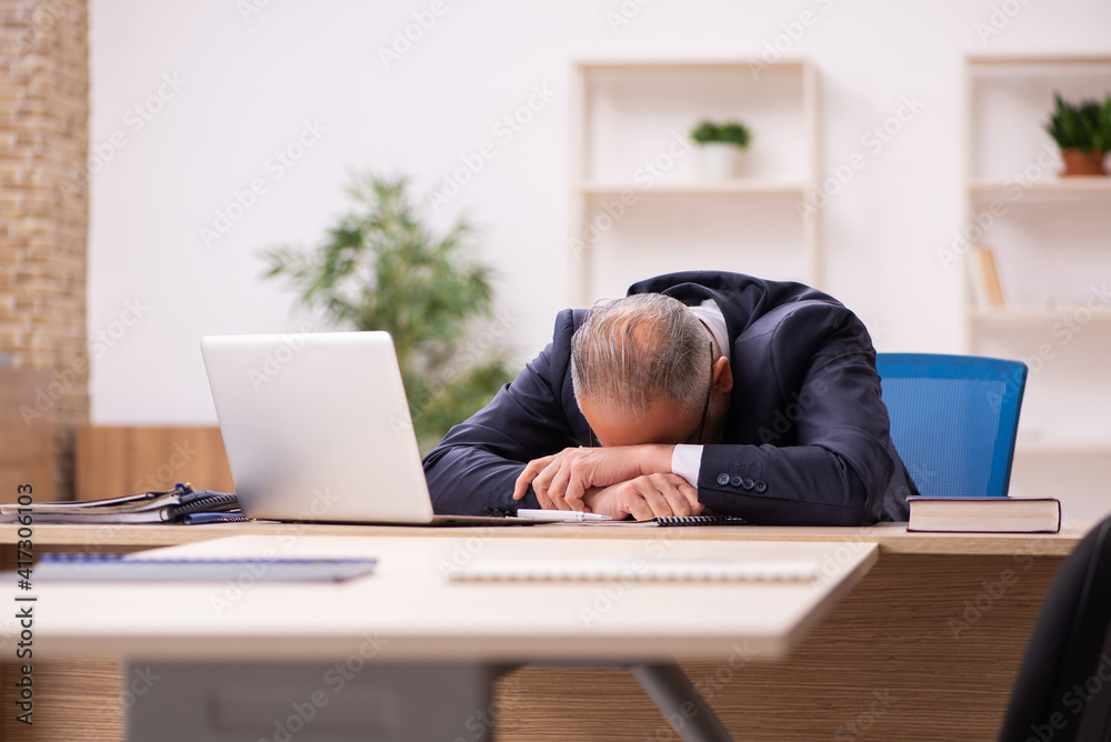 Old male employer sitting in the office Old male employer sitting in the office