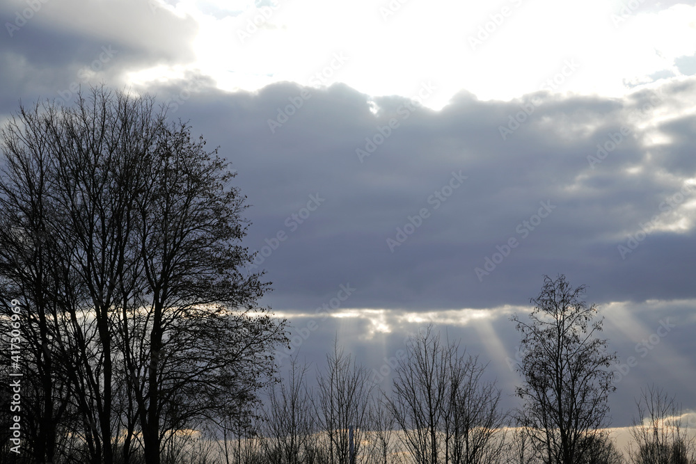 Sonnenstrahlen brechen durch die Wolkendecke am Abend. Landschaftsaufnahme in bewölkter abendlicher Stimmung im Naturschutzgebiet Am Tibaum in der Nähe von Hamm. Sonnenstrahlen brechen durch die Wolkendecke am Abend. Landschaftsaufnahme in bewölkter abendlicher Stimmung im Naturschutzgebiet Am Tibaum in der Nähe von Hamm.