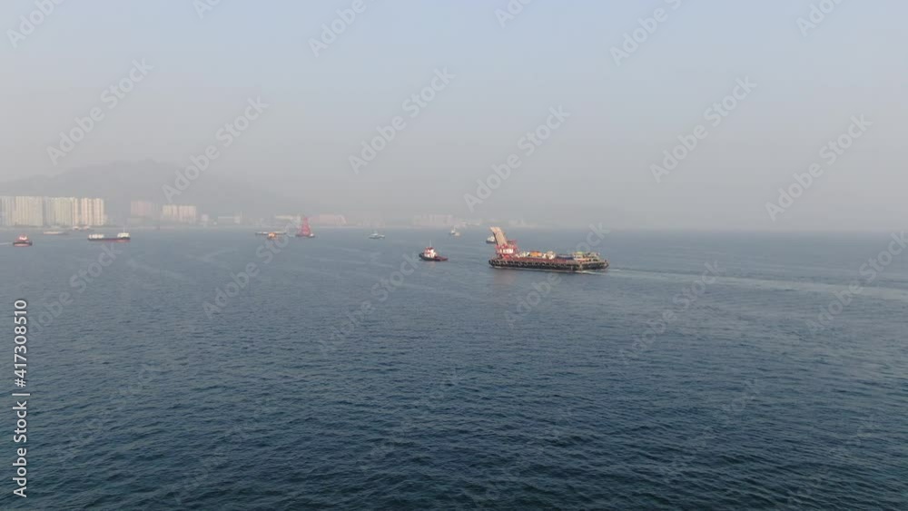Barge loaded with Concrete mixer trucks pulled to port by a Tugboat in Hong Kong bay, Aerial view. Barge loaded with Concrete mixer trucks pulled to port by a Tugboat in Hong Kong bay, Aerial view.