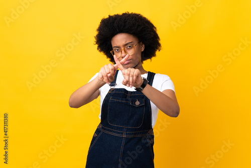 Young African American woman isolated on yellow background making stop gesture with her hand to stop an act