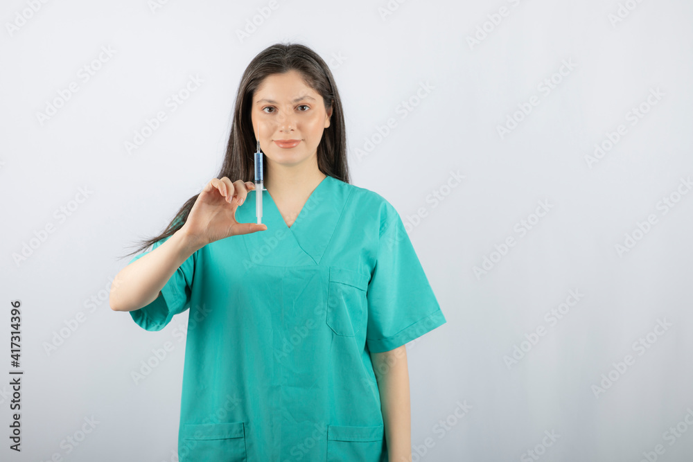 Portrait of female doctor holding a large syringe. Portrait of female doctor holding a large syringe.
