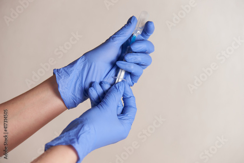 hands of a medical worker in blue gloves close-up with a vaccine syringe