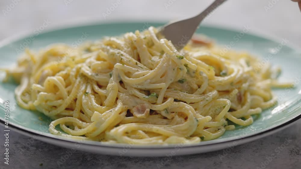 Close up on fresh spaghetti carbonara on plate. Noodles are rolled on a fork