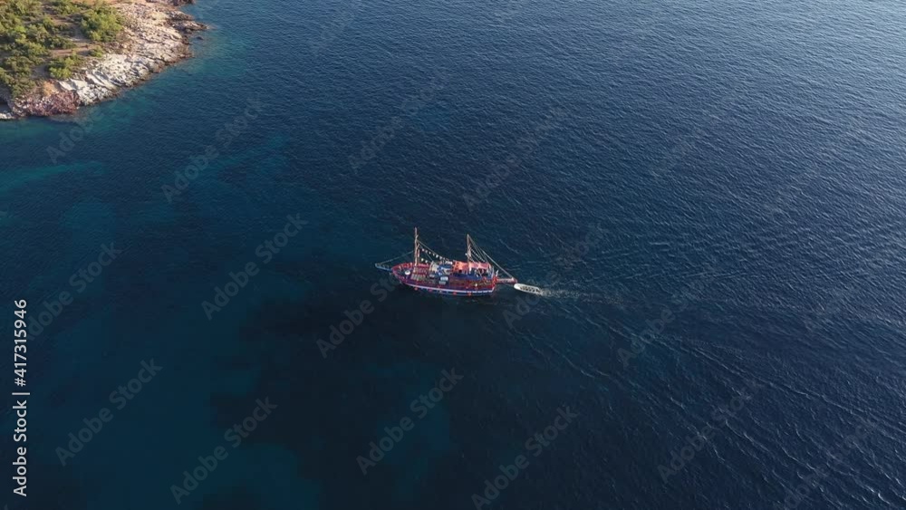 Aerial view of a tourist cruise ship sailing near the rocky Mediterranean coast of the Greek island Aerial view of a tourist cruise ship sailing near the rocky Mediterranean coast of the Greek island