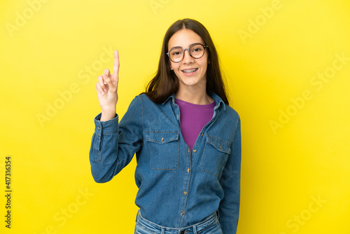 Young French woman isolated on yellow background pointing up a great idea