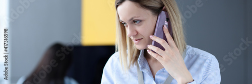 Woman talking on cell phone and looking at laptop