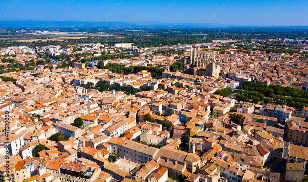 Scenic panoramic aerial view of residential areas of Narbonne with medieval Roman Catholic Cathedral on sunny summer day, France