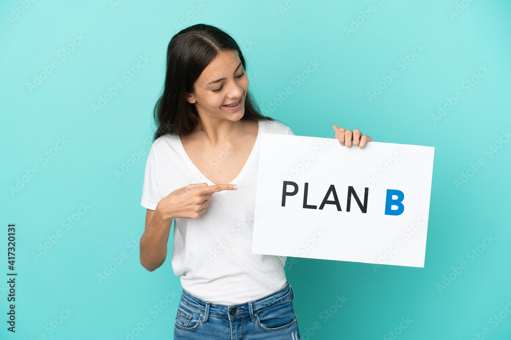 Young French woman isolated on blue background holding a placard with the message PLAN B Young French woman isolated on blue background holding a placard with the message PLAN B
