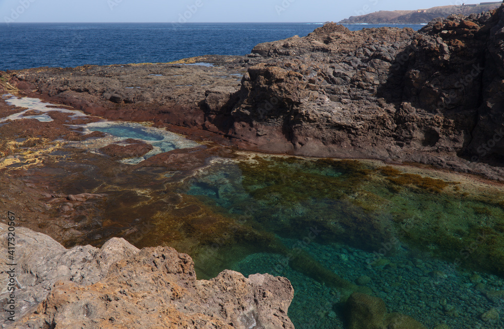 Fototapeta premium Gran Canaria, calm natural seawater pools in under the steep cliffs of the north coast and separated from the ocean by volcanic rocks, Sardina del Norte area 