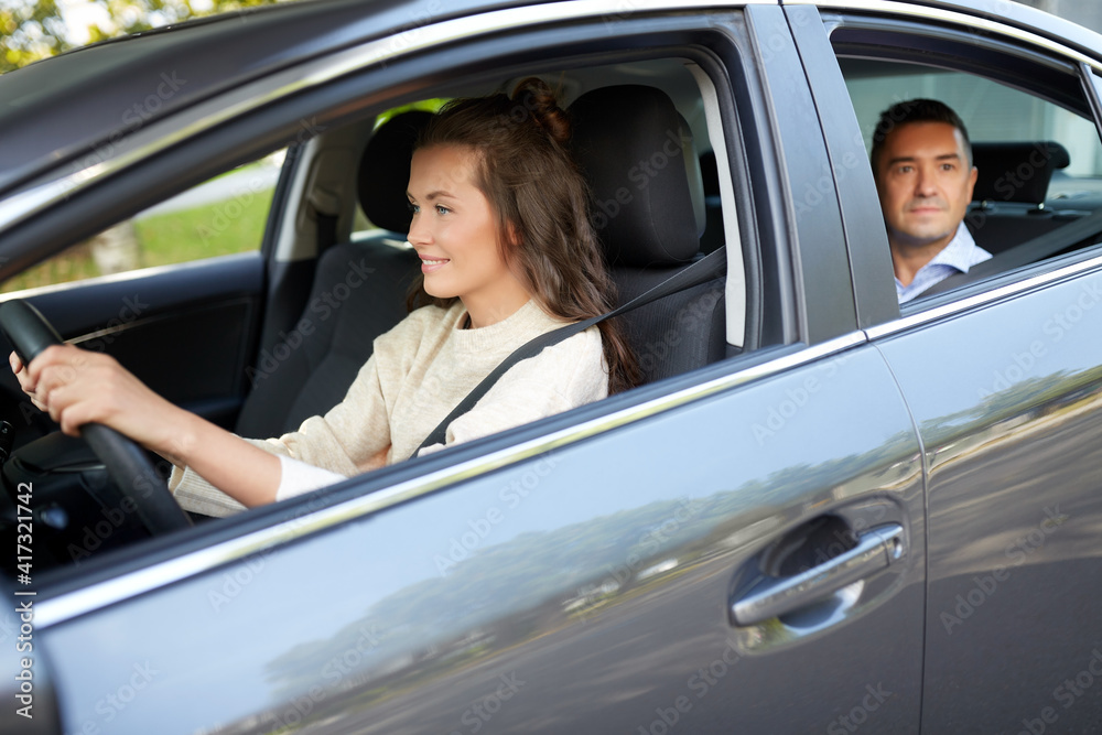 transportation, vehicle and people concept - happy smiling female driver driving car with male passenger