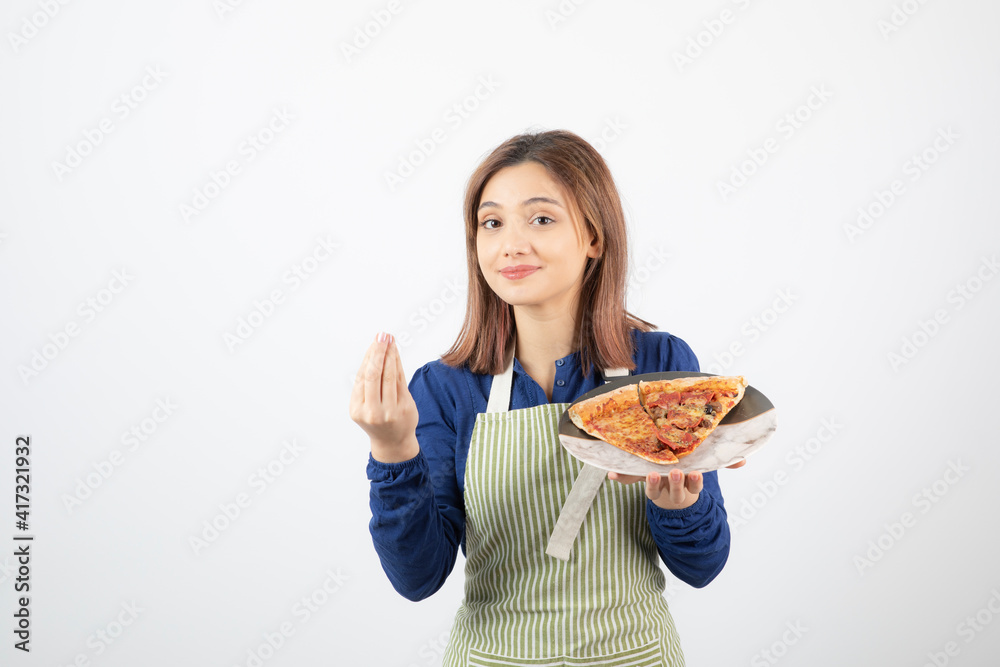 Portrait of woman in kitchen apron showing plate of pizza on white background Portrait of woman in kitchen apron showing plate of pizza on white background